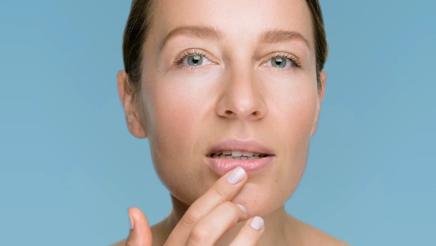 A woman touching her lip against a blue background