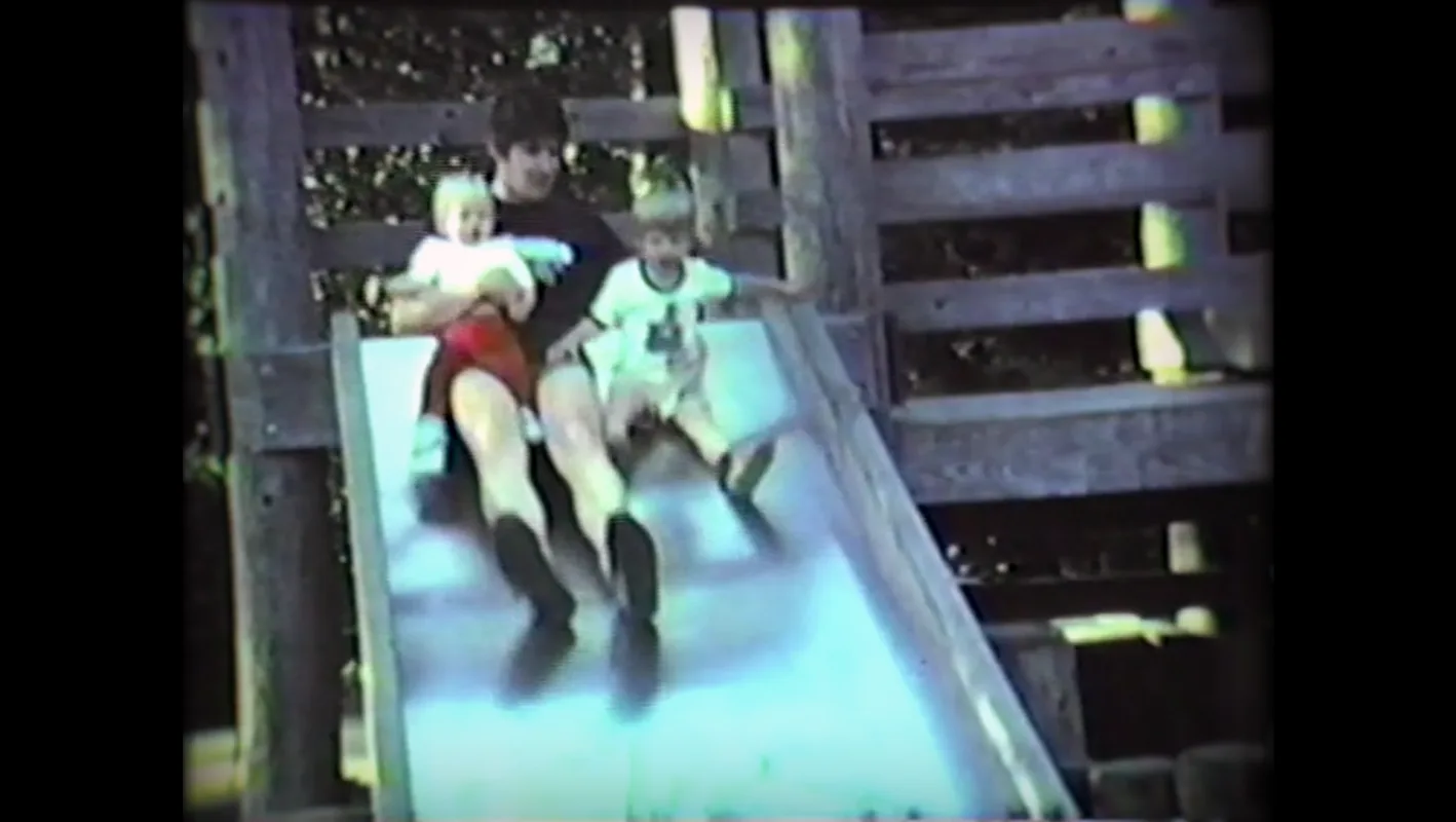 A family captured in a vintage home video while going down a slide